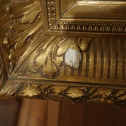 Detail of ornate gilt frame corner showing carved acanthus motif and area of gesso loss